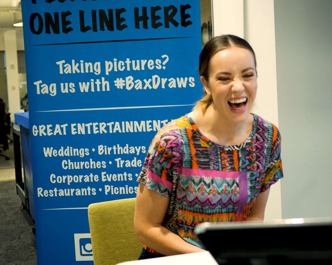 Guest laughing while a Bax Illustration artist draws her caricature at an event